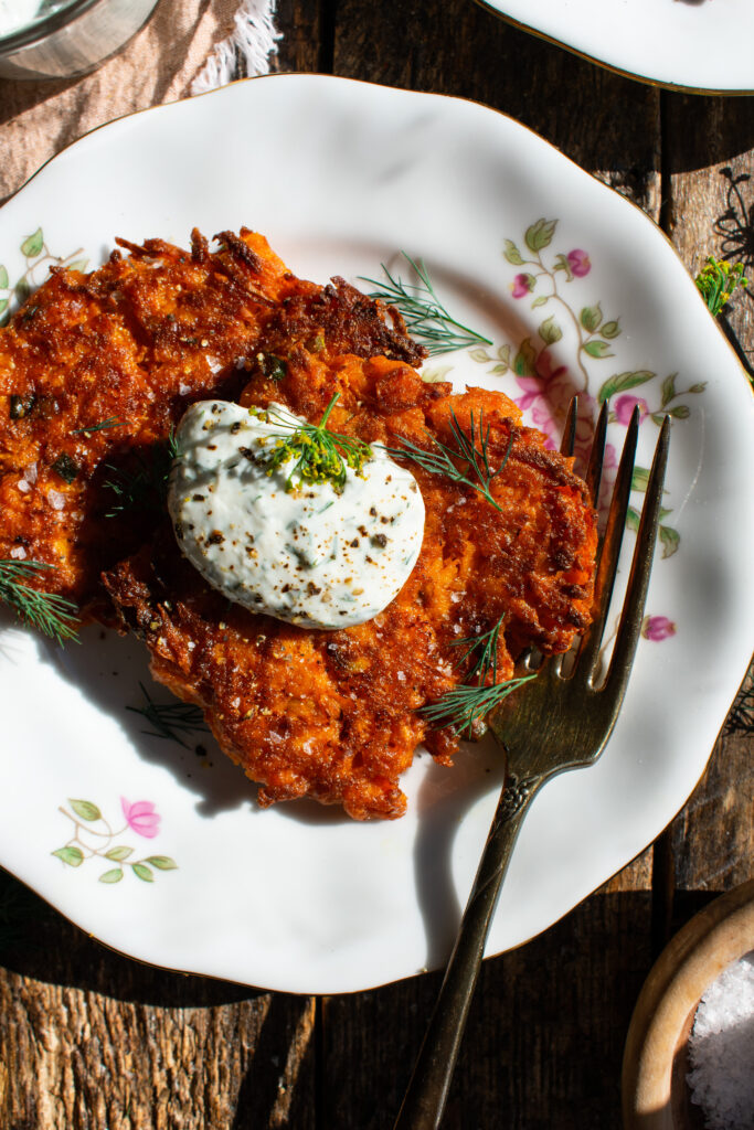 two Sweet Potato Fritters on a plate with a dollop of dill yogurt sauce